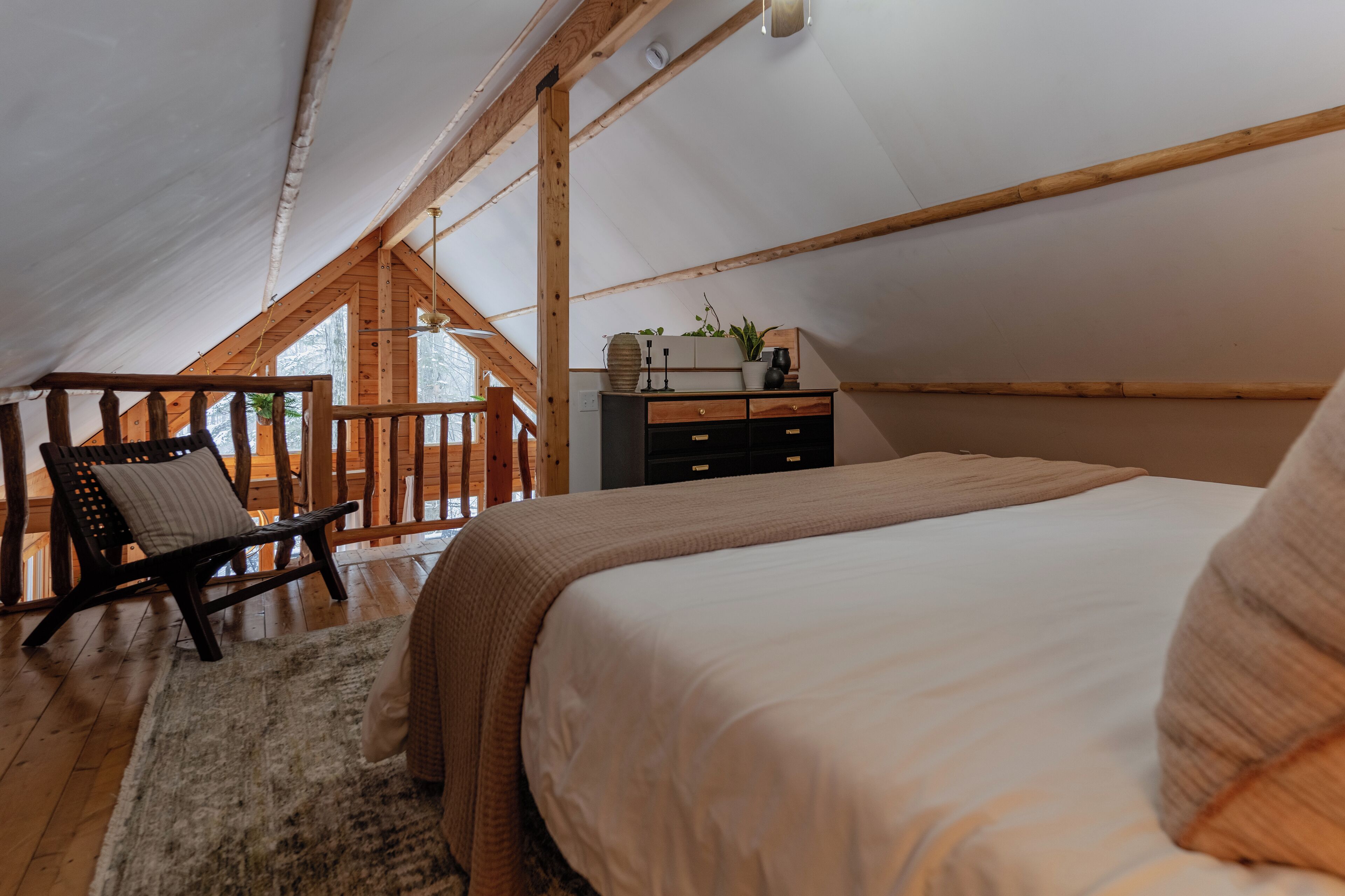 A cozy bedroom with a large bed, wooden furniture, and a view of the outdoors.