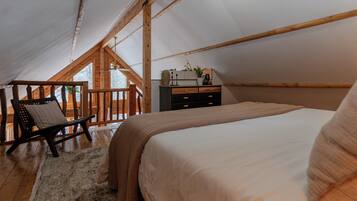 A cozy bedroom with a large bed, wooden furniture, and a view of the outdoors.