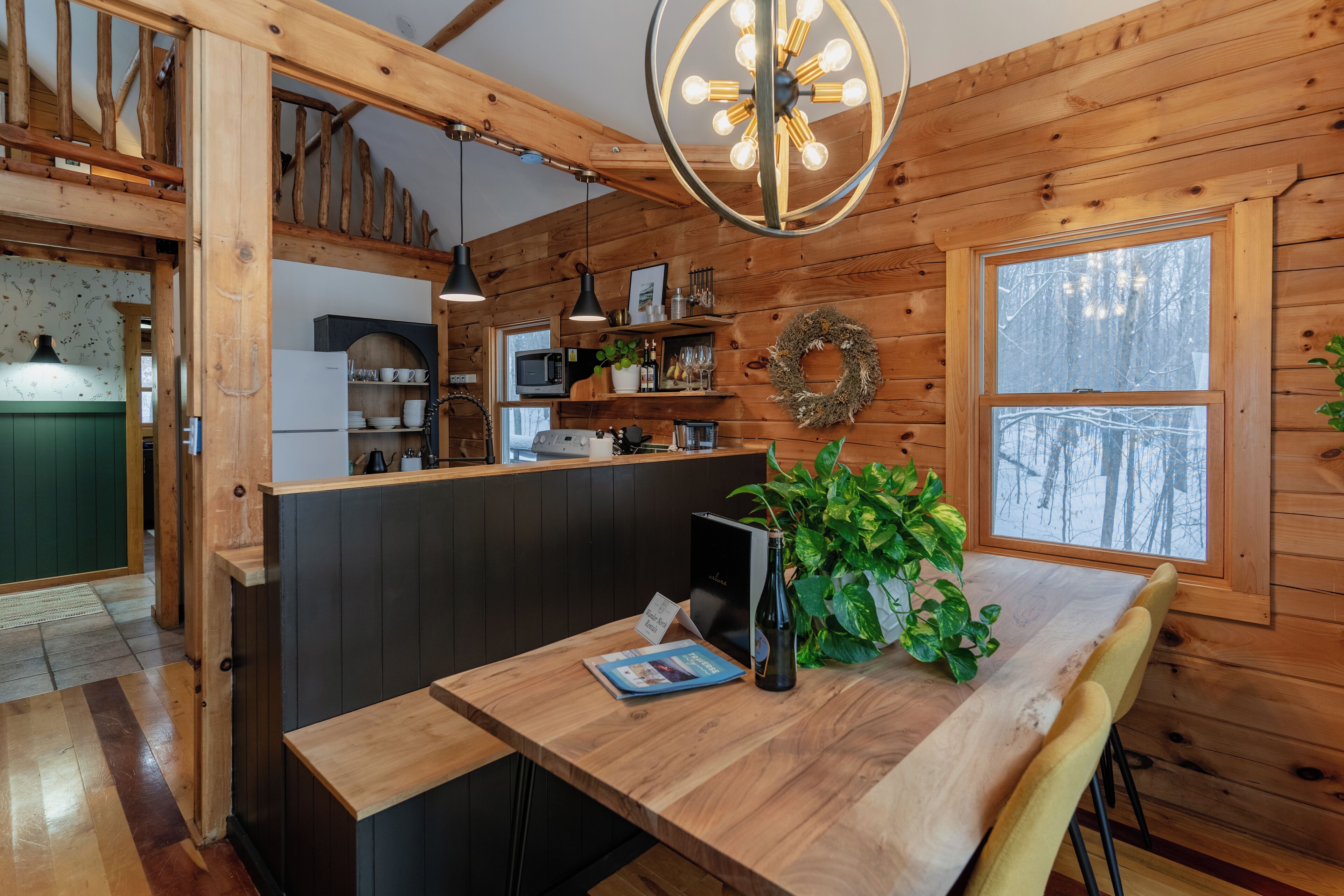 Ein Holzinterieur mit einem Holztisch, einem Blumentopf und Blick ins Freie durch ein Fenster.