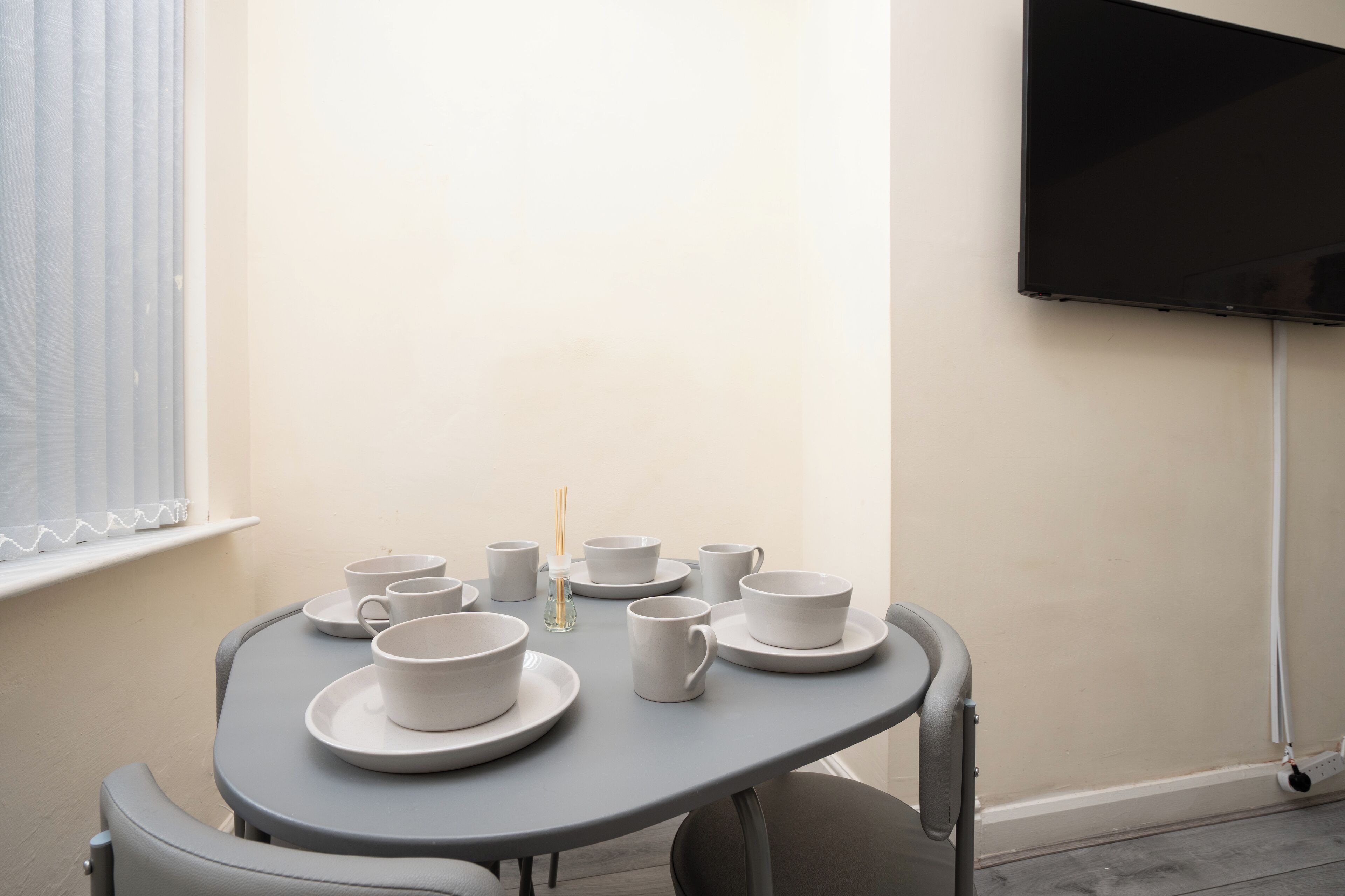 A small table with white cups and saucers, a small bottle, and a candle.