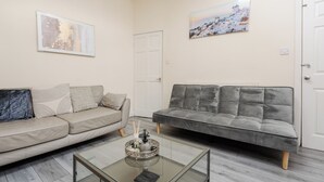 Ein Wohnzimmer mit zwei Sofas, einem Glastisch und einem Gemälde an der Wand.