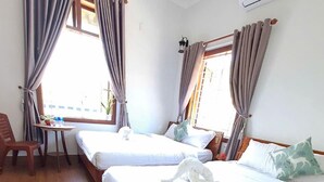A hotel room with two beds, a small table, a chair, and a potted plant. - Cong Man Homestay - Cham Island (Da Nang)