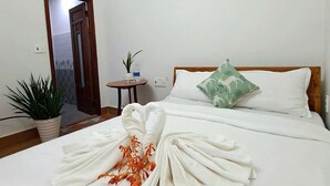 A hotel room with a neatly made bed, an air conditioning unit, a bedside table with a plant, and a wall-mounted lamp. - Cong Man Homestay - Cham Island (Da Nang)