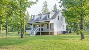Een wit huis met twee verdiepingen, een veranda en een trap naar de bovenverdieping.