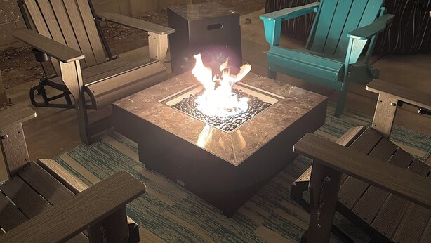 Eine Terrasse im Freien mit Feuerschale, Sitzgelegenheiten und Lichterketten.