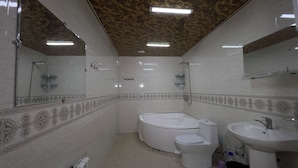 Een badkamer met bad, toilet en wastafel, met tegelwerk met een patroon en een plafond met luipaardprint.