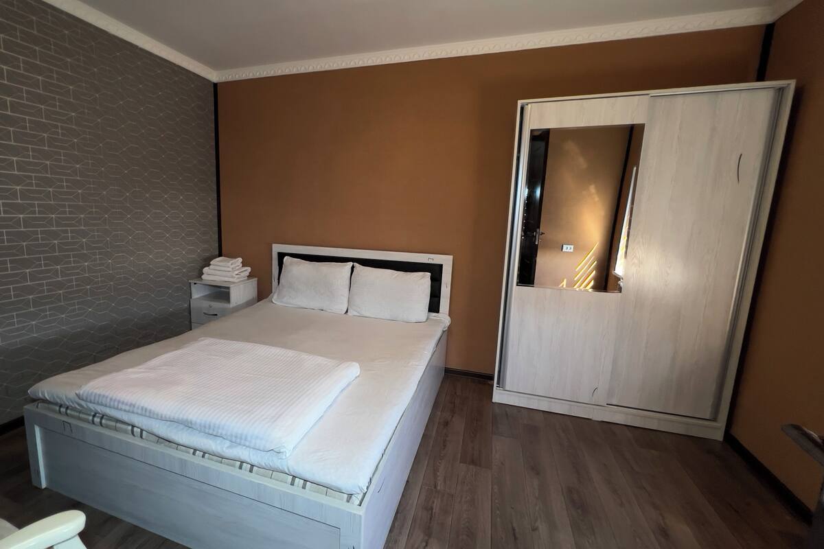 A neatly made bed with white linens, a wooden headboard, and a bedside table with a lamp.