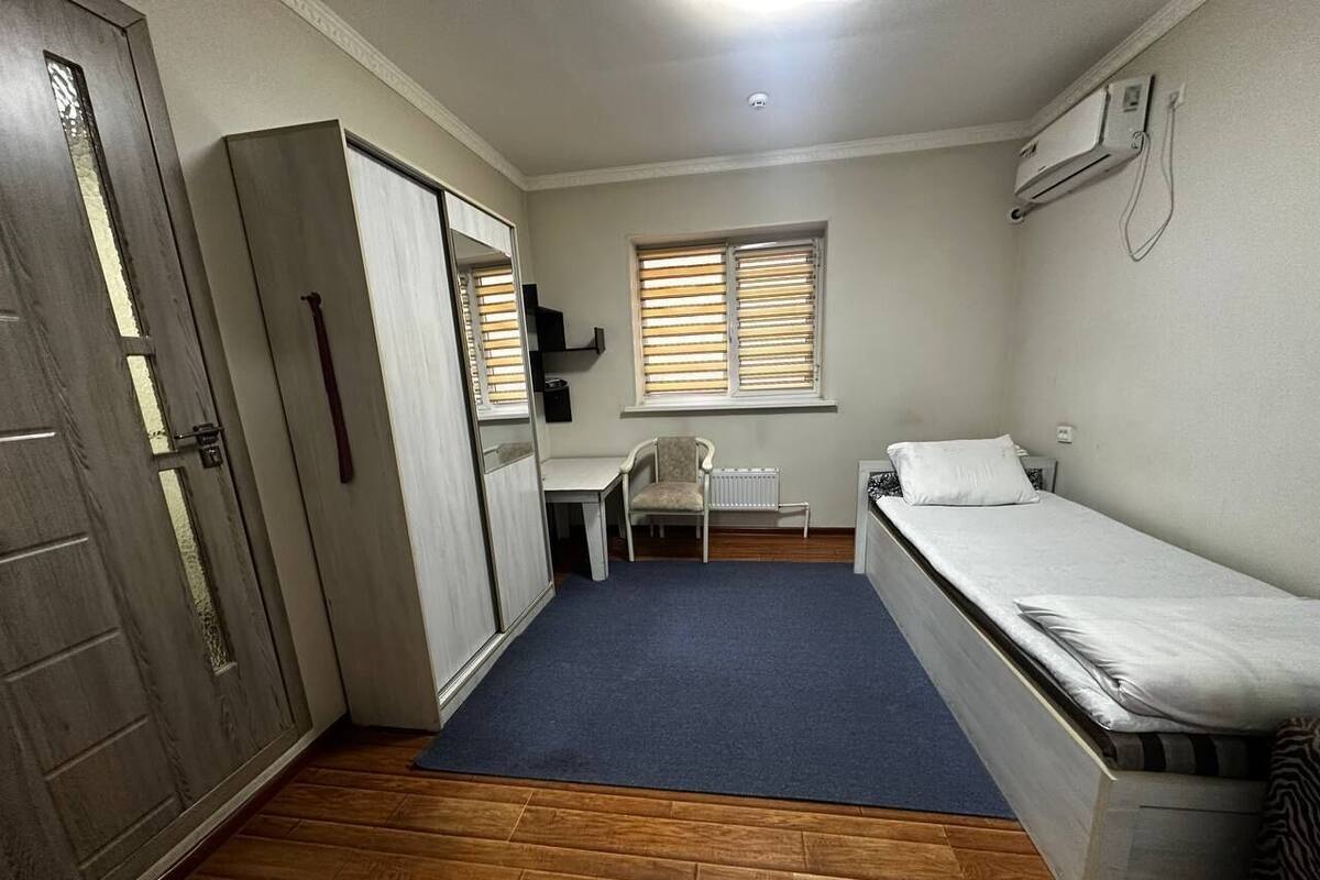 A compact room with a single bed, a desk, a chair, and a radiator.