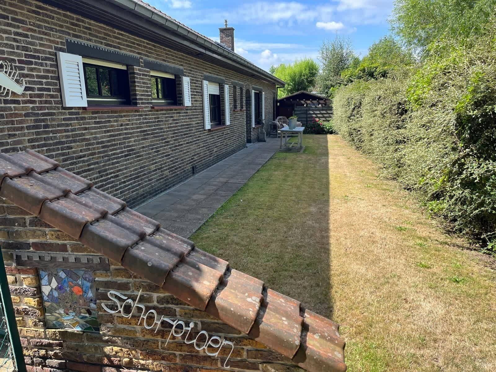 Een gebouw van baksteen met pannendak, een kleine tuin en een houten hek.