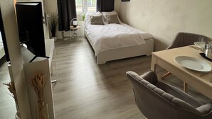 Una habitación de hotel moderna con cama, escritorio con silla, televisor y ventana con cortinas.