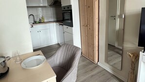 Una cocina moderna con armarios blancos, techo de madera y un comedor con mesa y silla.