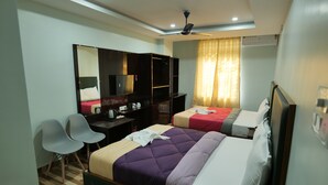 A hotel room with two beds, a desk, a chair, a wardrobe, and a ceiling fan. - Hotel HK Regency (Guwahati)