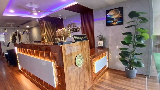 A hotel reception desk with a wooden finish, a reception sign, and a framed picture on the wall. - Hotel HK Regency (Guwahati)