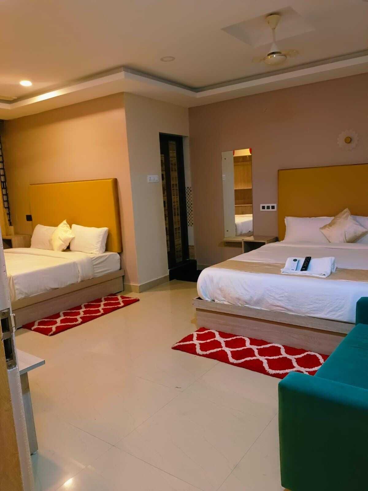 A hotel room with two beds, a ceiling fan, and a red and white patterned rug.