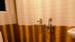 A bathroom with a toilet, a sink, and a shower area. - Hotel HK Regency (Guwahati)