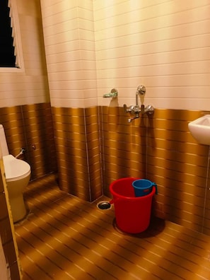 A bathroom with a toilet, a sink, and a shower area. - Hotel HK Regency (Guwahati)