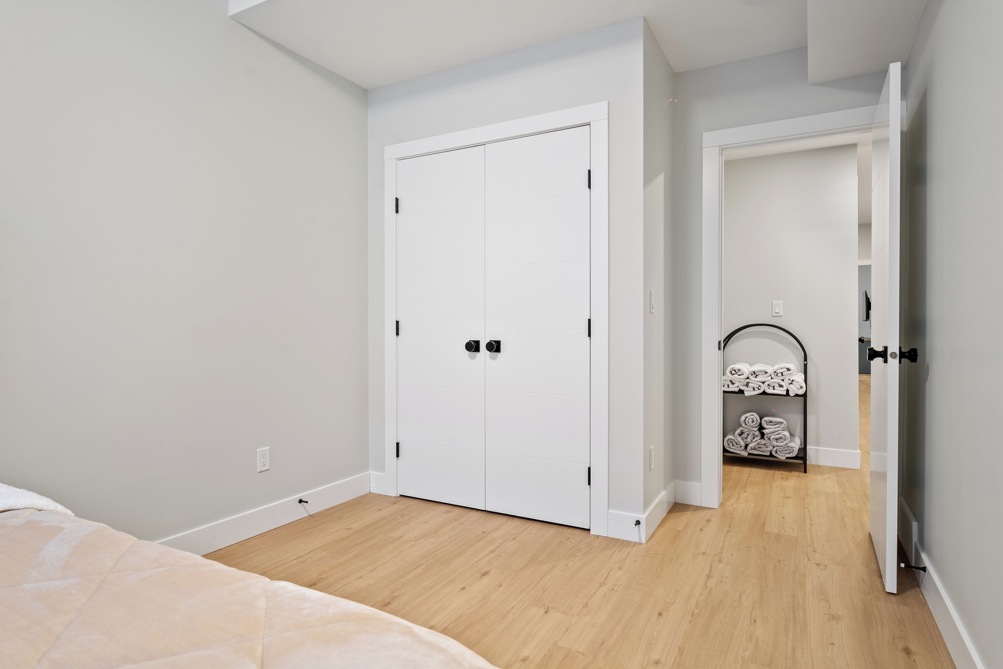 Une chambre à coucher avec un lit, une armoire blanche et un plancher en bois.