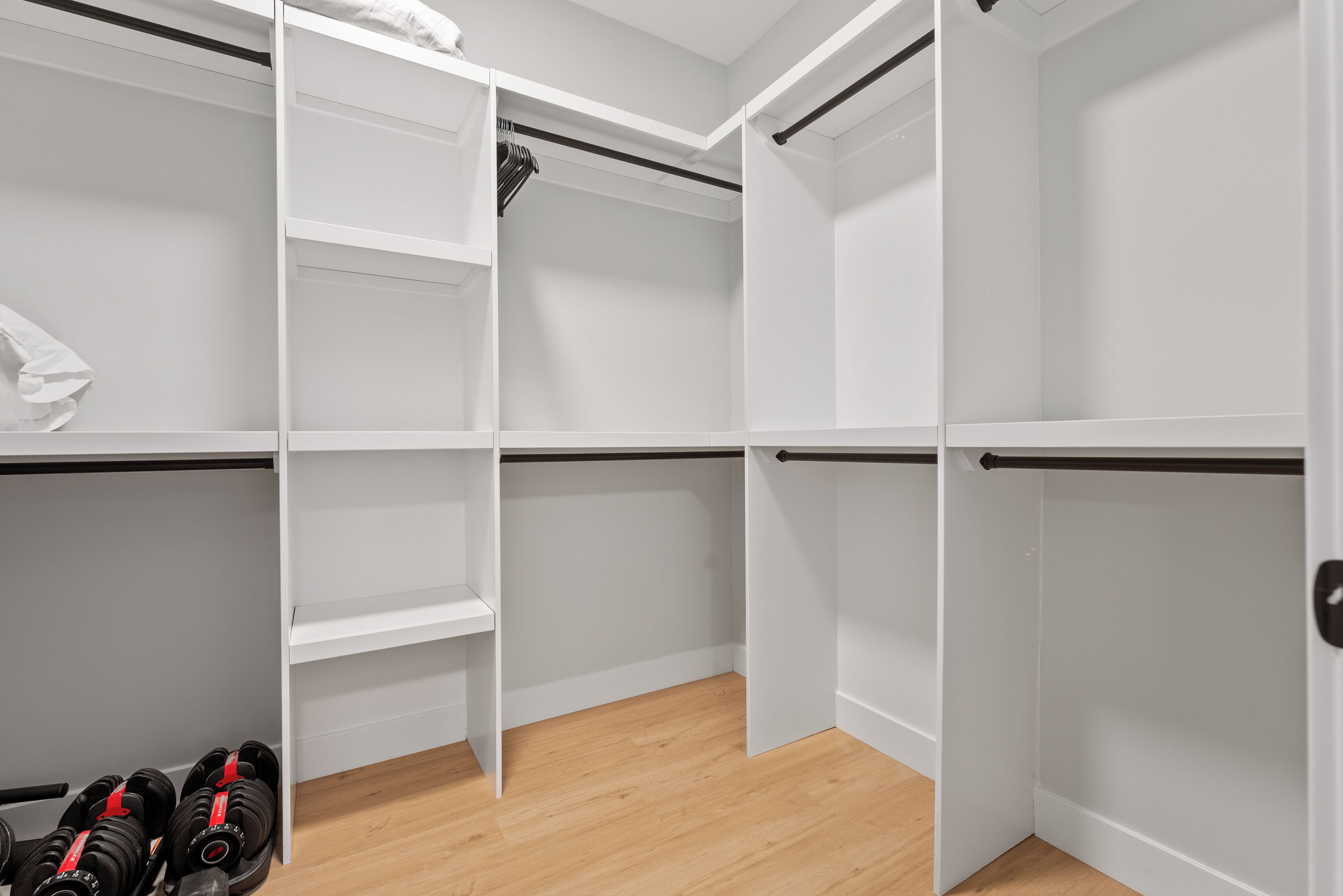 Un placard blanc, dont les portes sont ouvertes, laissant apparaître des étagères et un espace pour suspendre des vêtements.