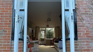 A spacious room with a brick wall, a wicker chair, a sofa, and a dining area with a table and chairs. - Thin End (Seaview)