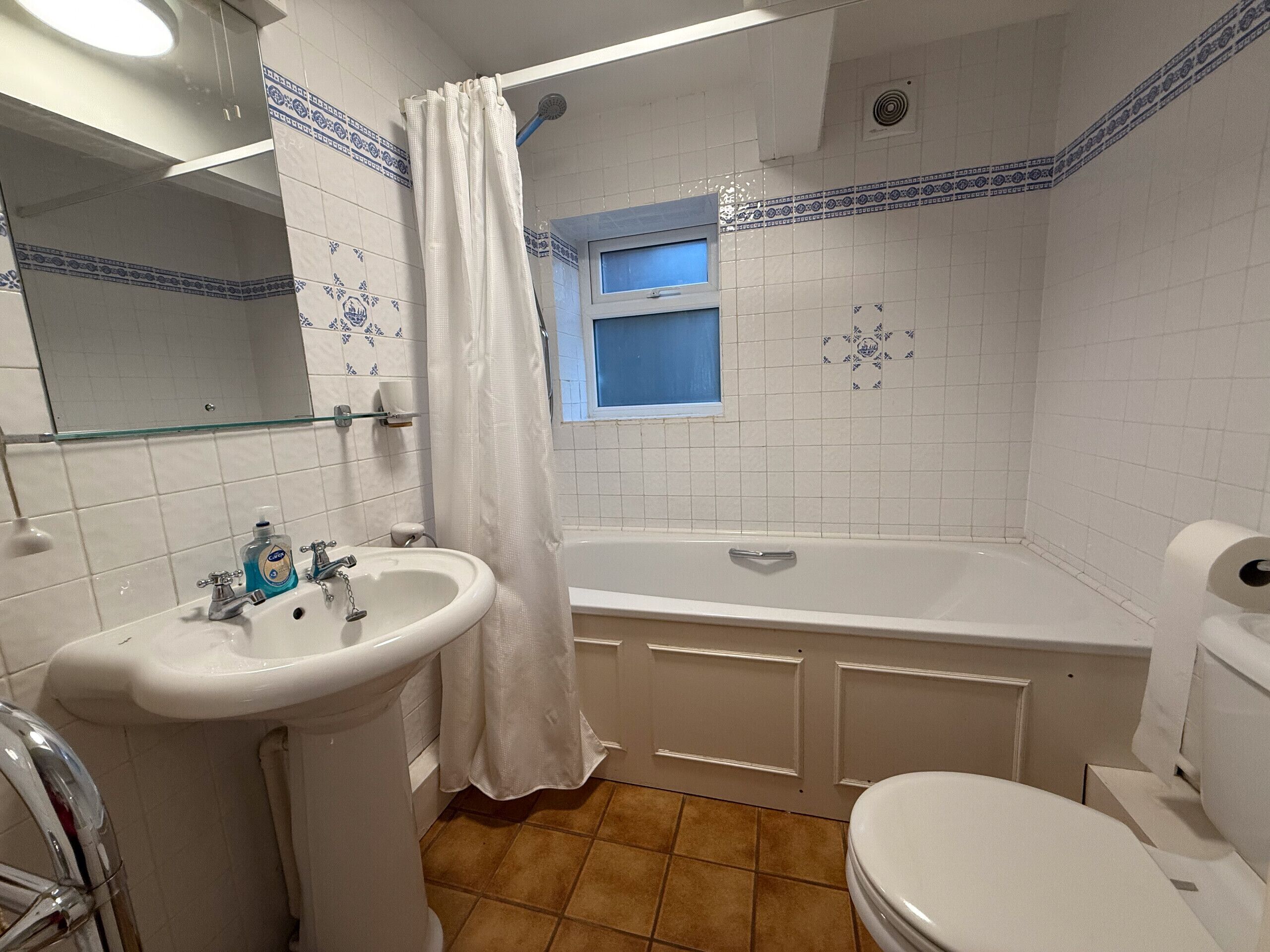 A bathroom with a sink, toilet, bathtub, and a shower curtain.