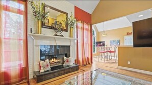 A living room with a fireplace, a glass coffee table, and a dining area with a TV. - Spacious and comfy 4 Bed/3 Full Bath Canton Home! (Canton)