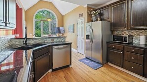 A kitchen with dark wooden cabinets, a stainless steel refrigerator, a microwave, and a dishwasher. - Spacious and comfy 4 Bed/3 Full Bath Canton Home! (Canton)