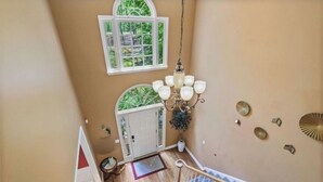 A staircase with a chandelier, a white door, and a view of greenery outside. - Spacious and comfy 4 Bed/3 Full Bath Canton Home! (Canton)