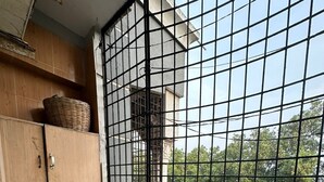 A corner room with a washing machine, a tiled wall, and a window with a metal grid.