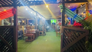 Un bar y restaurante con un letrero sobre la entrada, muebles de madera y piso verde.