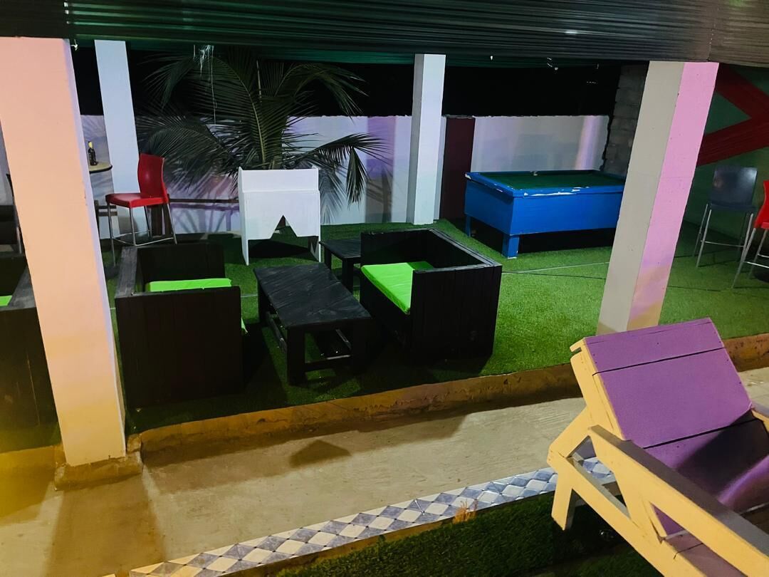 An indoor recreational area with artificial grass, a pool table, and seating arrangements.