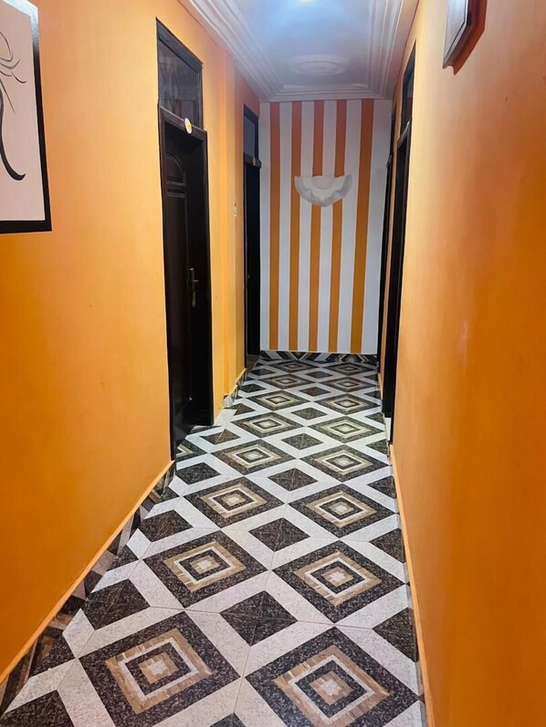 A hallway with orange walls, a striped wall, and a patterned floor.