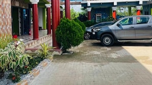 Un edificio de dos pisos con fachada verde, columnas rojas y un balcón.
