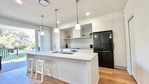 A modern kitchen with a large island, white cabinetry, and a black refrigerator.
