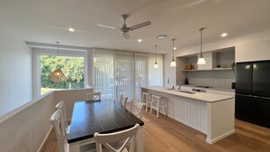 A modern kitchen with a dining area, white cabinetry, a black refrigerator, and pendant lighting.