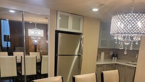 A modern kitchen with a refrigerator, a dining area with chairs, and a chandelier. - 2-bedroom villa hotel in phenomenal Las Vegas with WiFi, AC, fitness room (Las Vegas)