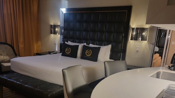 A hotel room with a large bed, a bedside table, a chair, a round table, and a bathroom visible through an open door. - 2-bedroom villa hotel in phenomenal Las Vegas with WiFi, AC, fitness room (Las Vegas)