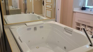 A bathroom with a large bathtub, a mirror, and a vanity with a sink. - 2-bedroom villa hotel in phenomenal Las Vegas with WiFi, AC, fitness room (Las Vegas)