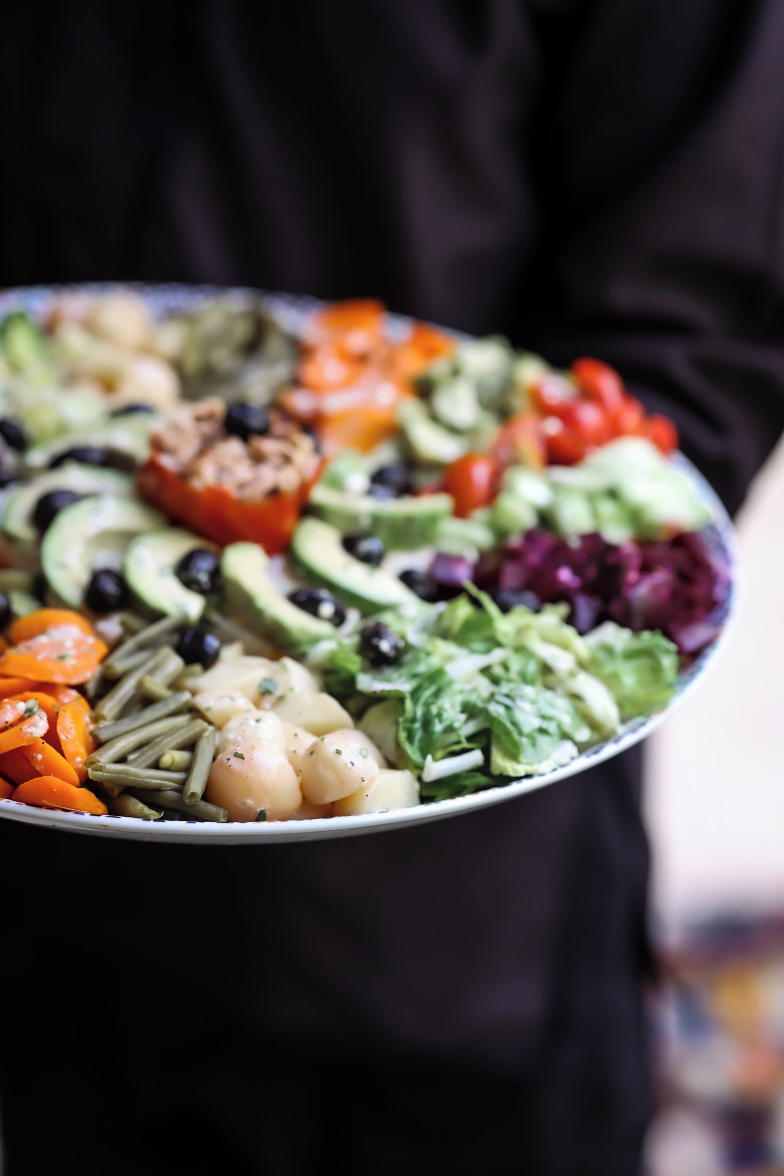 A bowl of colorful salad with various vegetables and a red pepper.