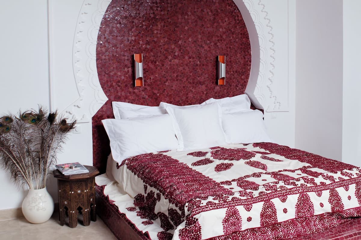 A bedroom with a large bed, a decorative wall, and a hanging light fixture.