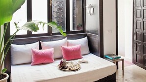 A bedroom with a large window, a bed with pink pillows, a potted plant, and a small table with a tray. - Ptit Habibi (Marrakech)