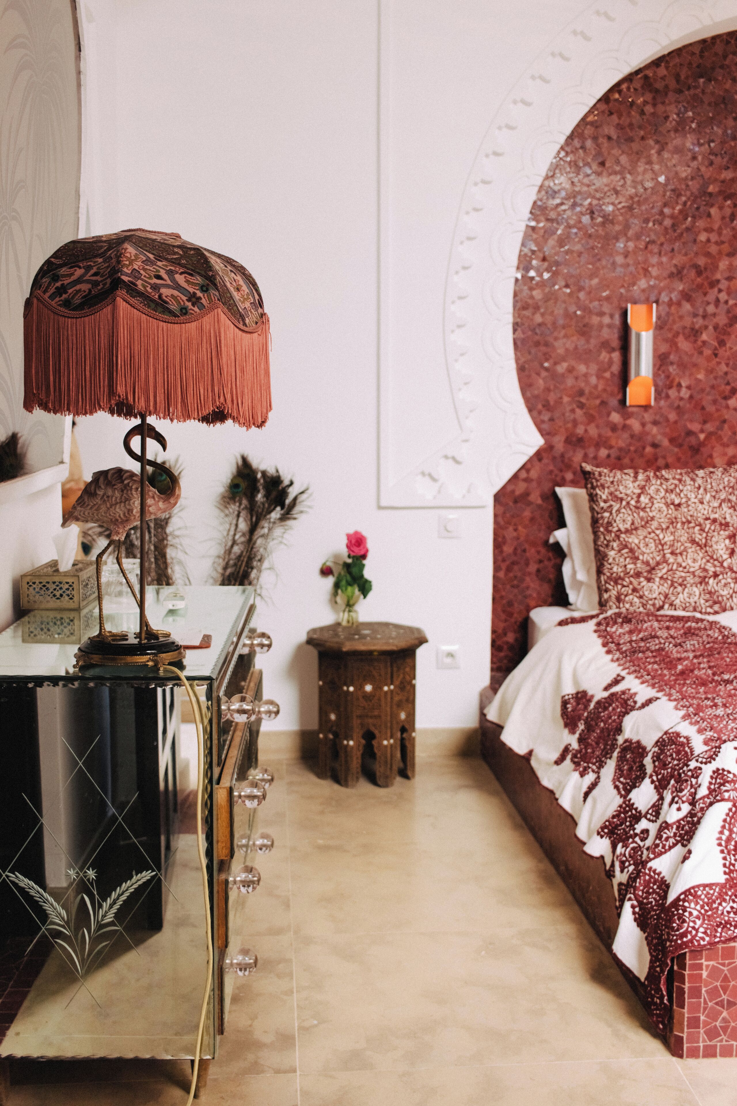 A bedroom with a bed, a nightstand, a lamp, and a dresser.