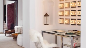 A modern interior with a glass table, a white chair, and a wall-mounted light fixture. - Ptit Habibi (Marrakech)