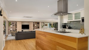 A modern kitchen with a wooden island, built-in appliances, and a grey hood.