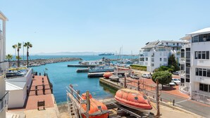 A marina with boats docked, a pier, and buildings with balconies overlooking the water.