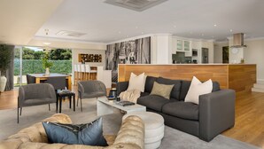 A modern living room with a grey sofa, a coffee table, and a dining area with chairs and a table.