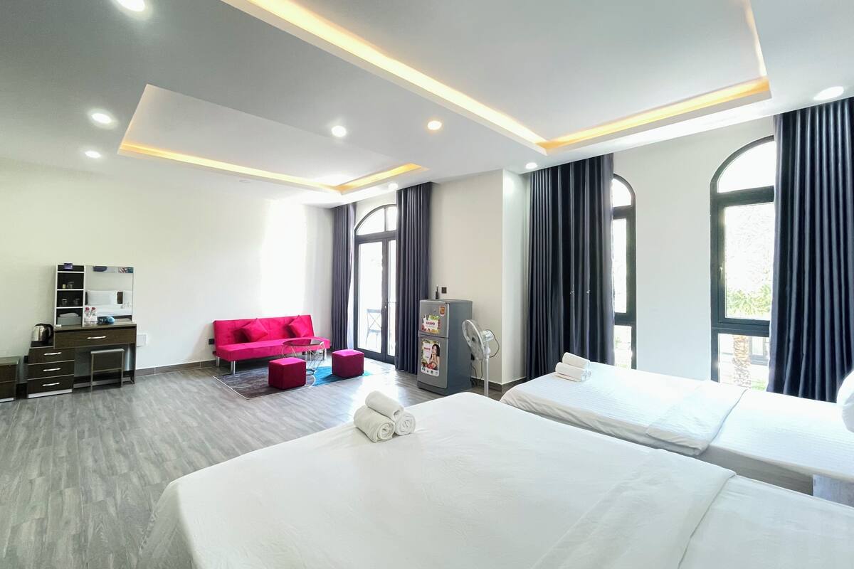 Une chambre d’hôtel avec deux lits, un bureau, une chaise, un canapé et un mini-bar.