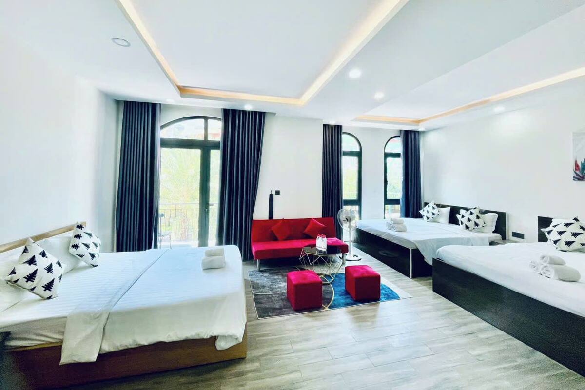 Une chambre d’hôtel moderne avec deux lits, un canapé rouge et une petite table.