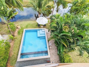 A rectangular swimming pool with steps leading into it, surrounded by lush greenery and palm trees. - Poolside Apartments and Rooms (Ko Chang)