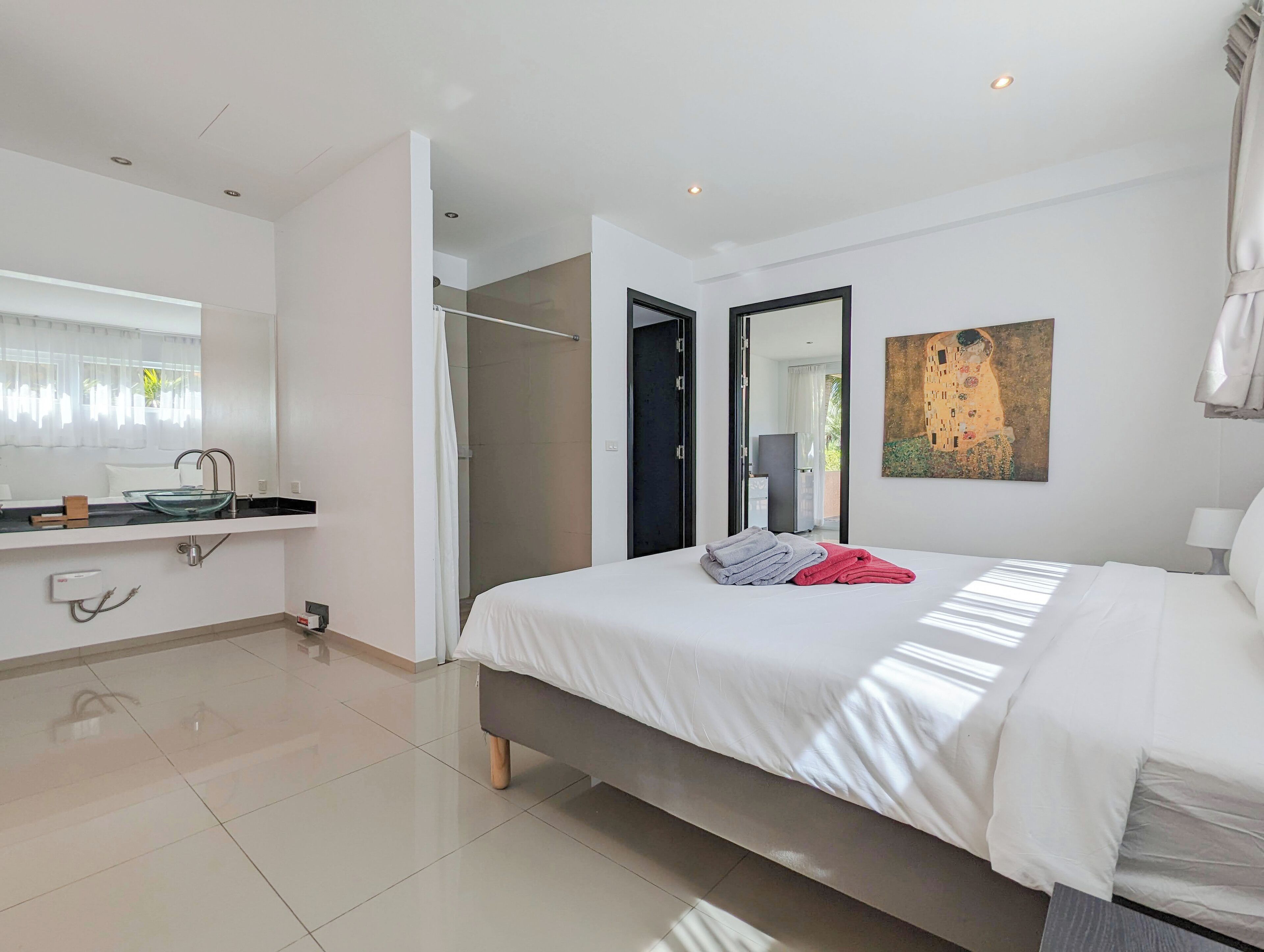 Une chambre à coucher moderne avec un grand lit, un lavabo intégré et un dressing.