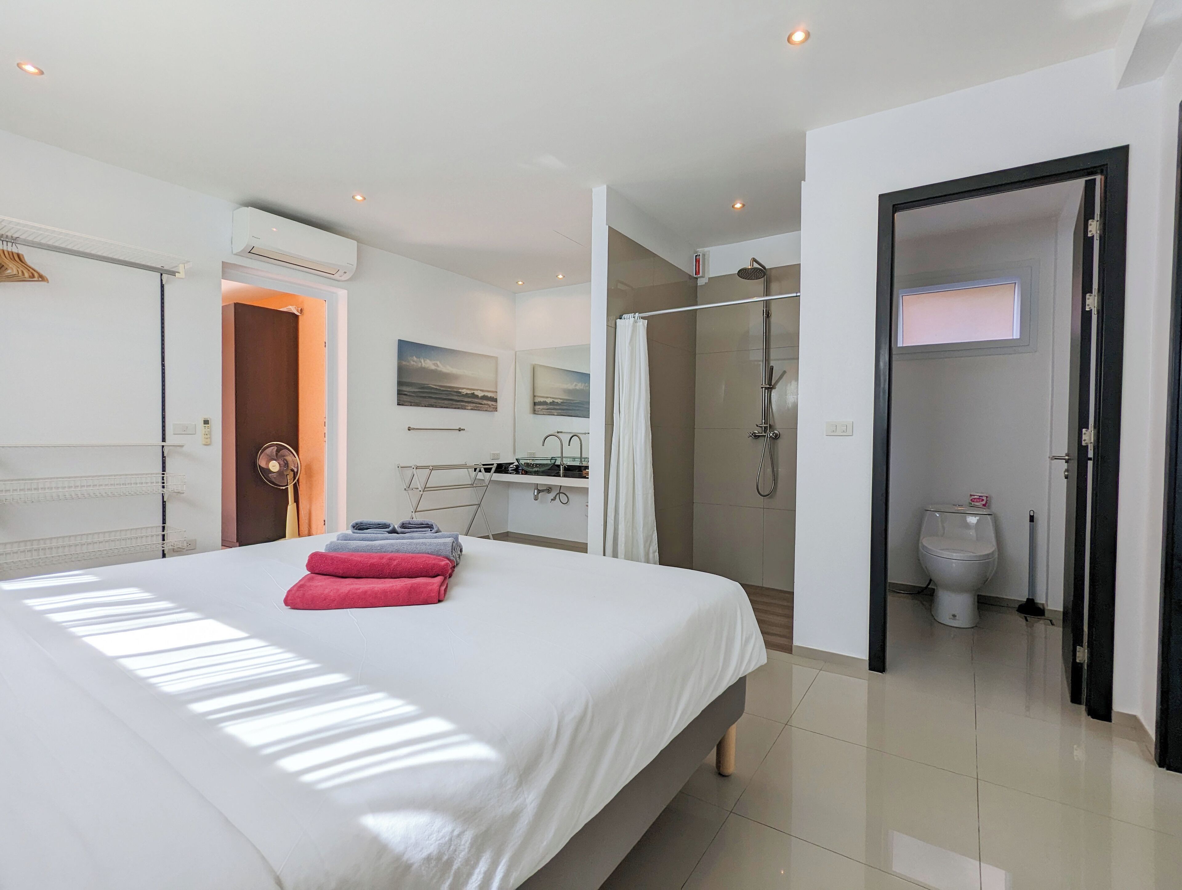 A modern hotel room with a large bed, a shower area, and a bathroom.